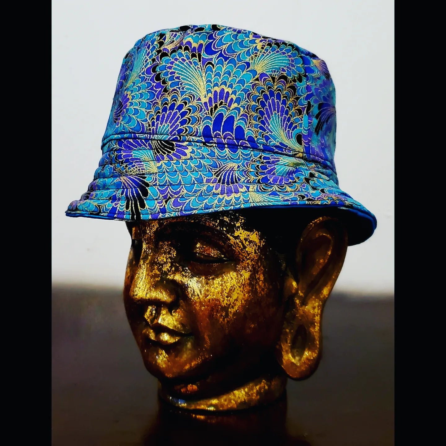 Reversed side view of Teal blue reversible leaf and peacock printed bucket hat