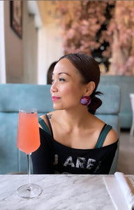 Model wearing Wine and Blue striped button earrings at a booth with a mimosa