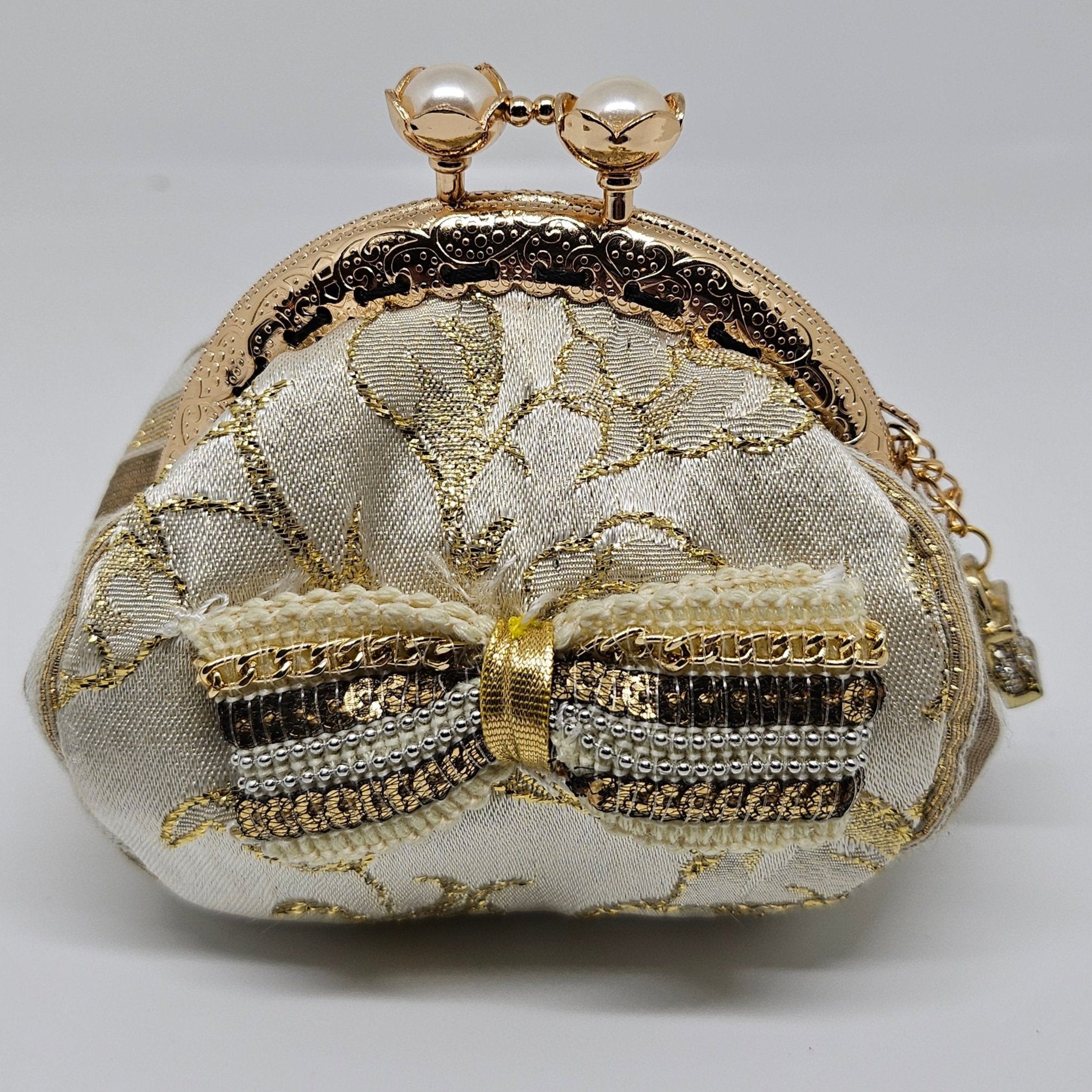 Front view of  Ivory and gold floral brocade kiss clasp coin purse with sequin and chain bow and ornate jeweled padlock charm