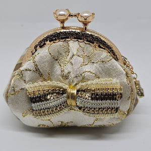 Front view of  Ivory and gold floral brocade kiss clasp coin purse with sequin and chain bow and ornate jeweled padlock charm
