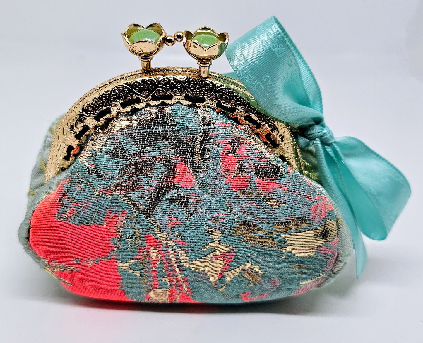 Front view of Mint and coral kiss clasp coin purse with laser etched ribbon bow