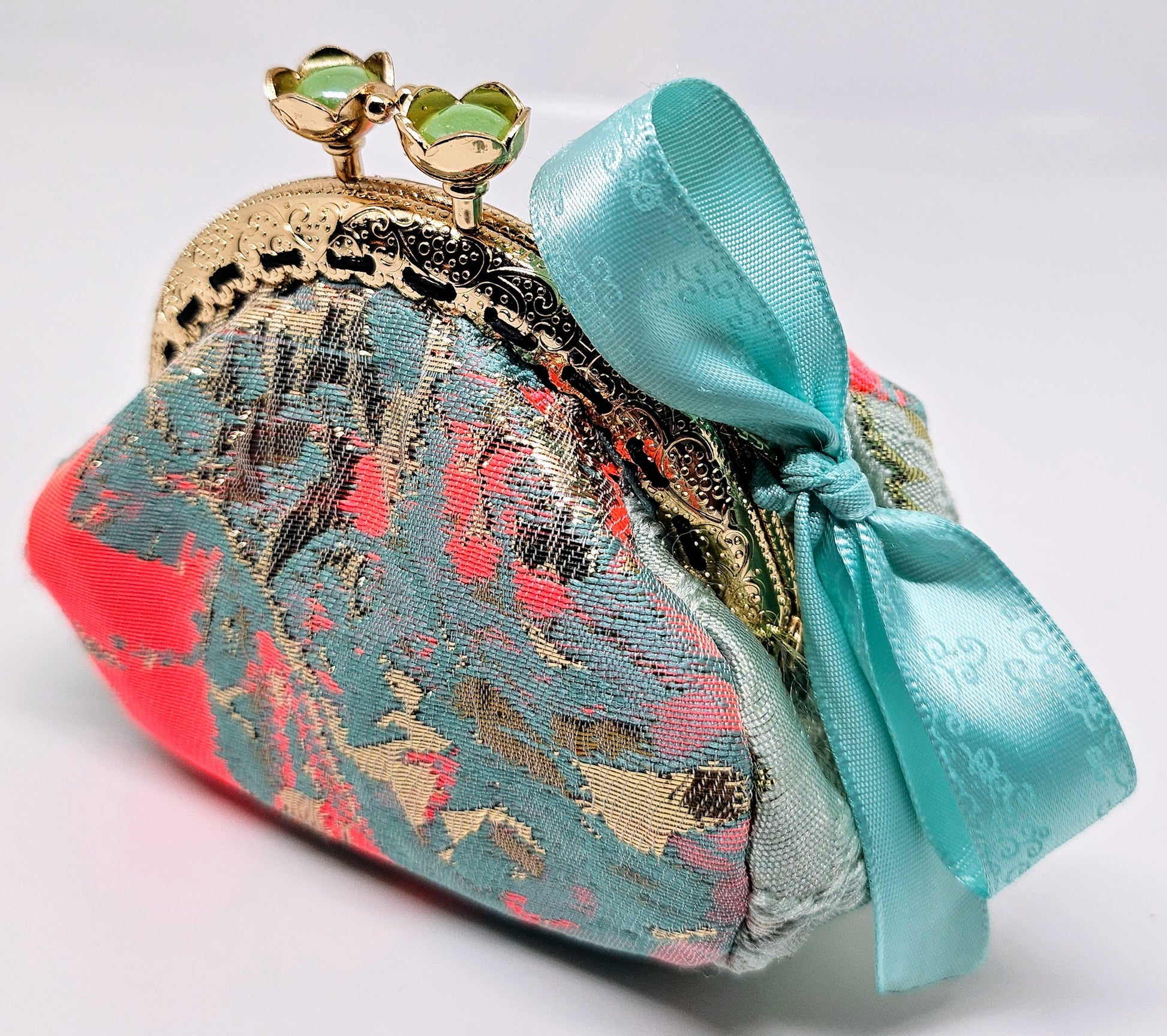Side view of Mint and coral kiss clasp coin purse with laser etched ribbon bow