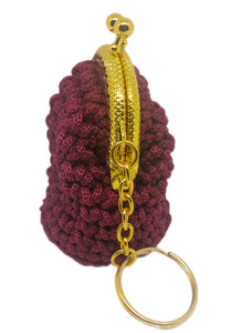 Side view of burgundy crochet coin purse keychain with gold kiss clasp frame.