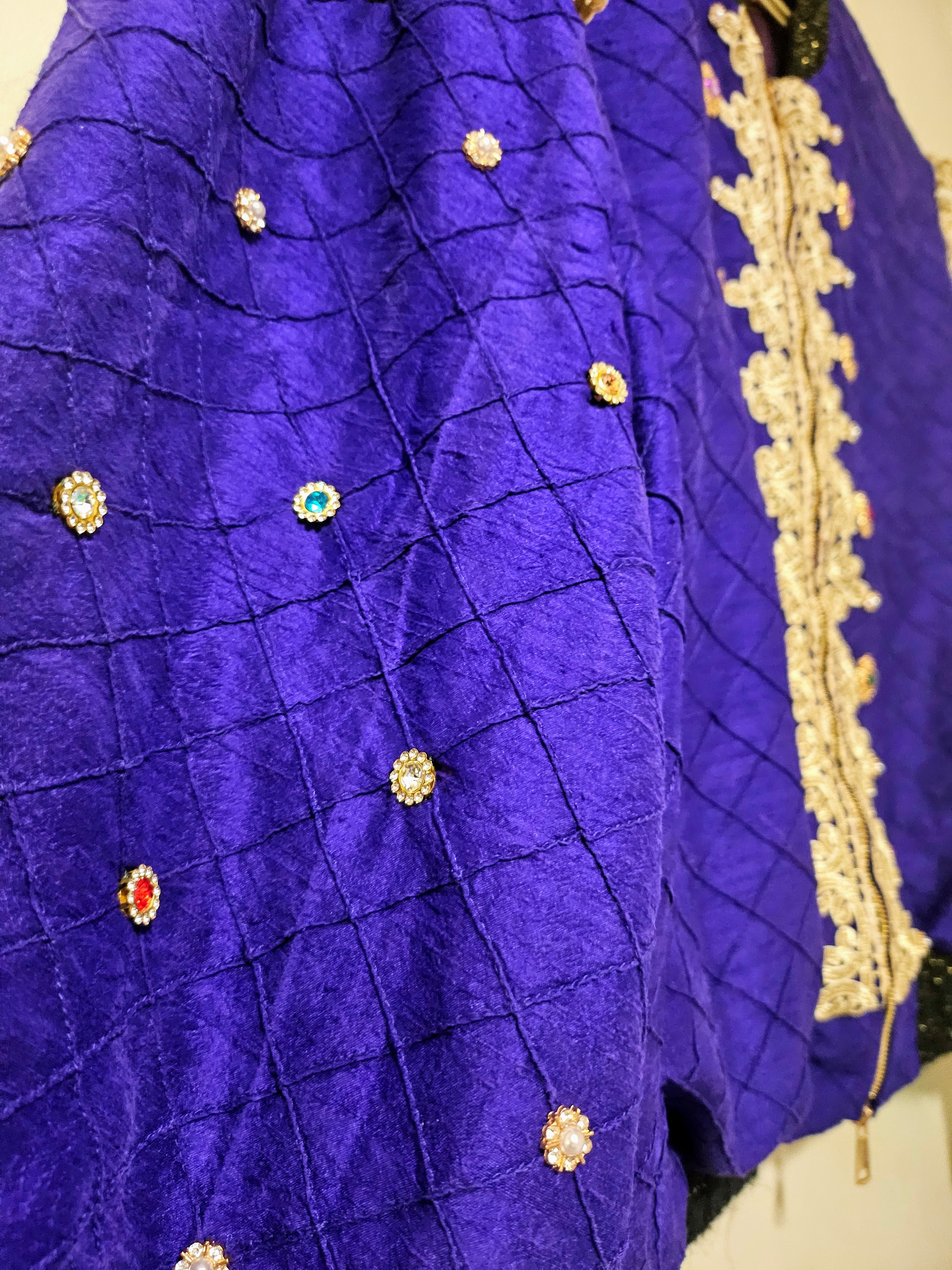 close up of sleeves of Rhinestone encrusted purple silk bomber jacket with gold lace accents