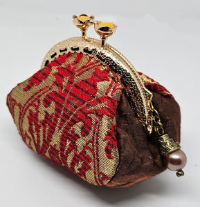 Side view of  Baroque print kiss clasp coin purse with ornate jeweled pearl charm. 