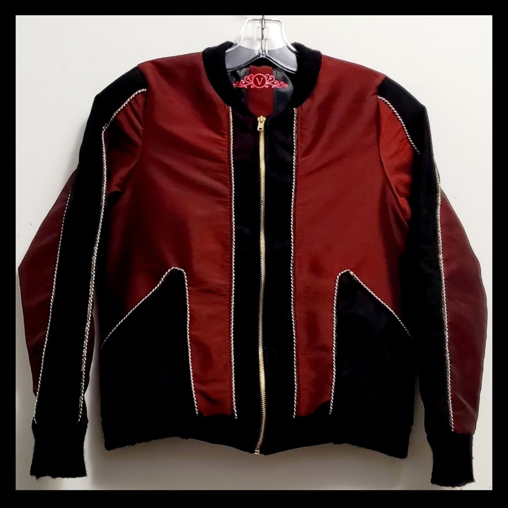 Front view of red taffeta and black velveteen colour-blocked bomber jacket with white cord piping
