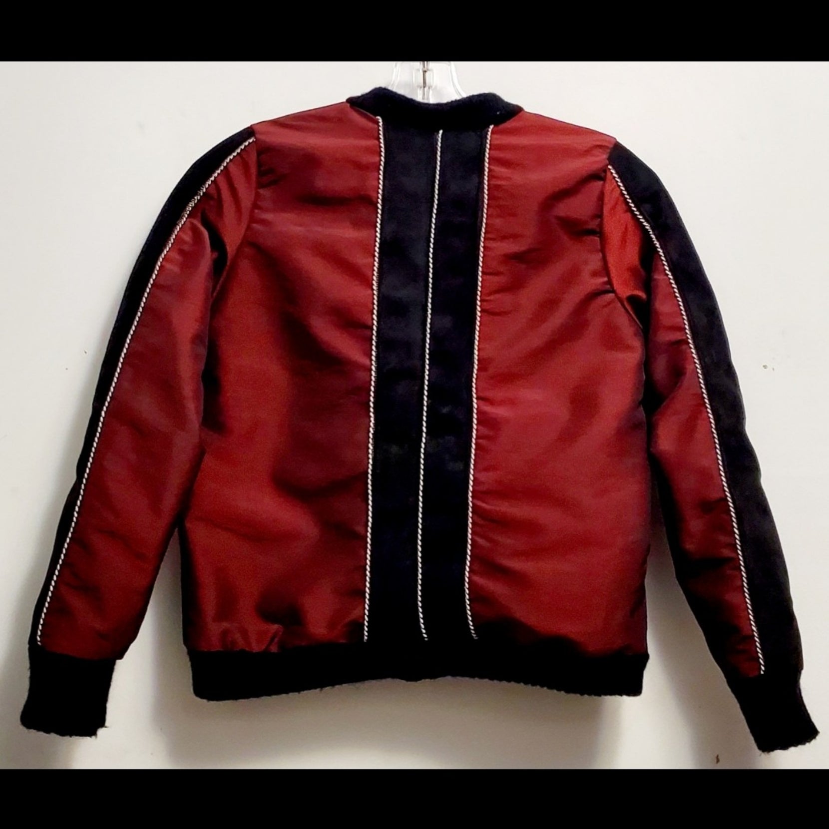 Back view of red taffeta and black velveteen colour-blocked bomber jacket with white cord piping