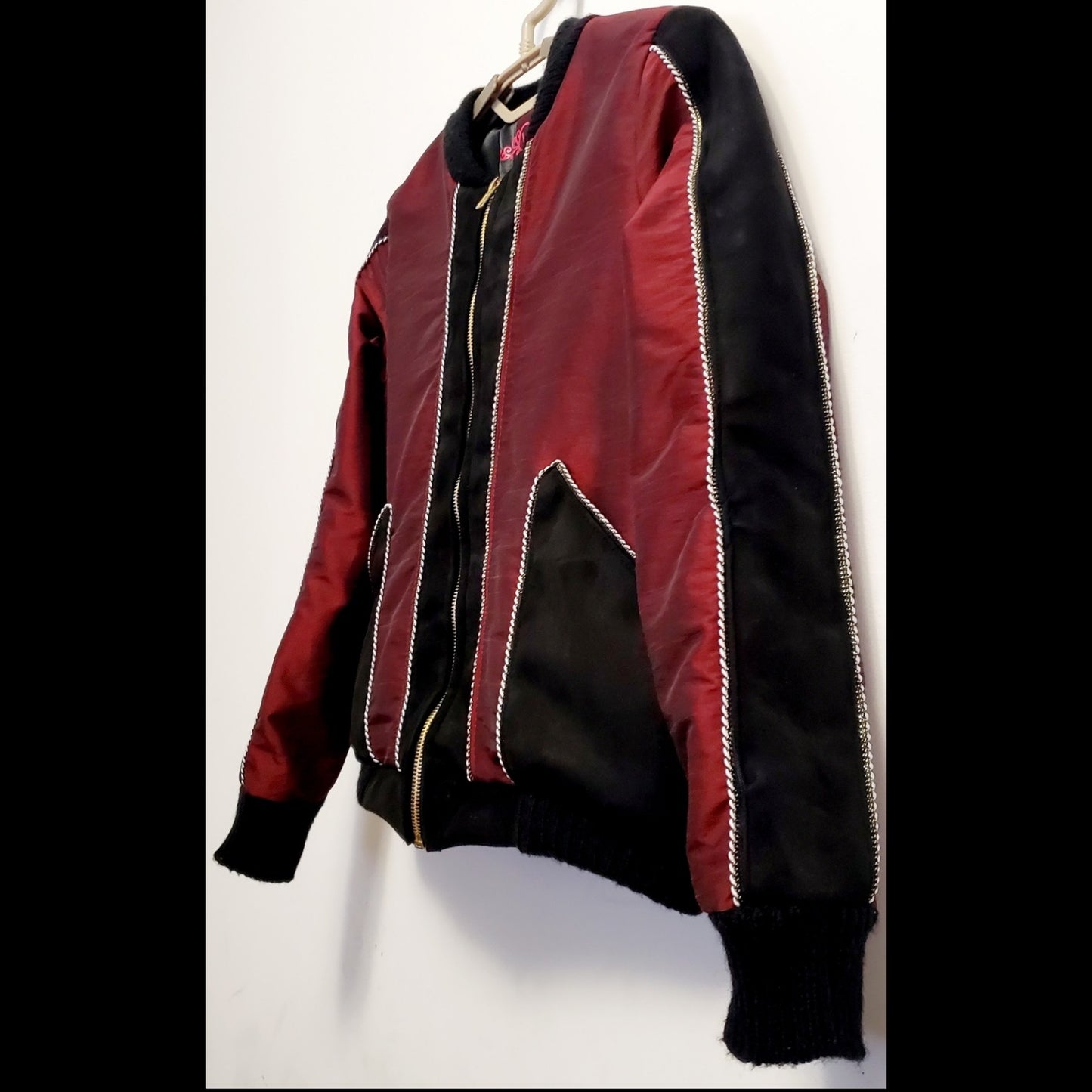 Side view of red taffeta and black velveteen colour-blocked bomber jacket with white cord piping