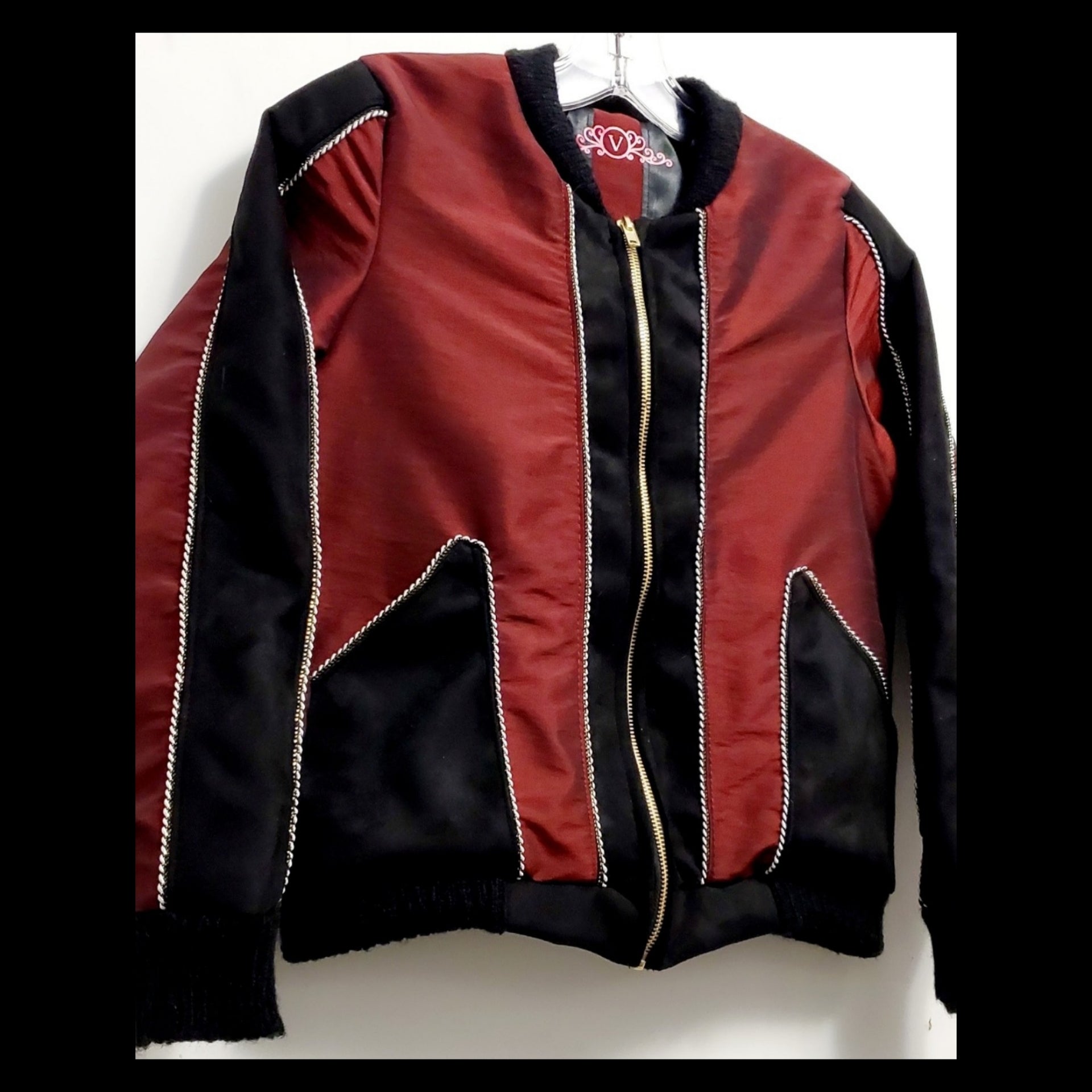 Close up front view of red taffeta and black velveteen colour-blocked bomber jacket with white cord piping