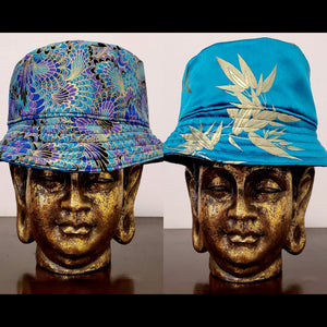 Side by side Front view of Teal blue reversible leaf and peacock printed bucket hat