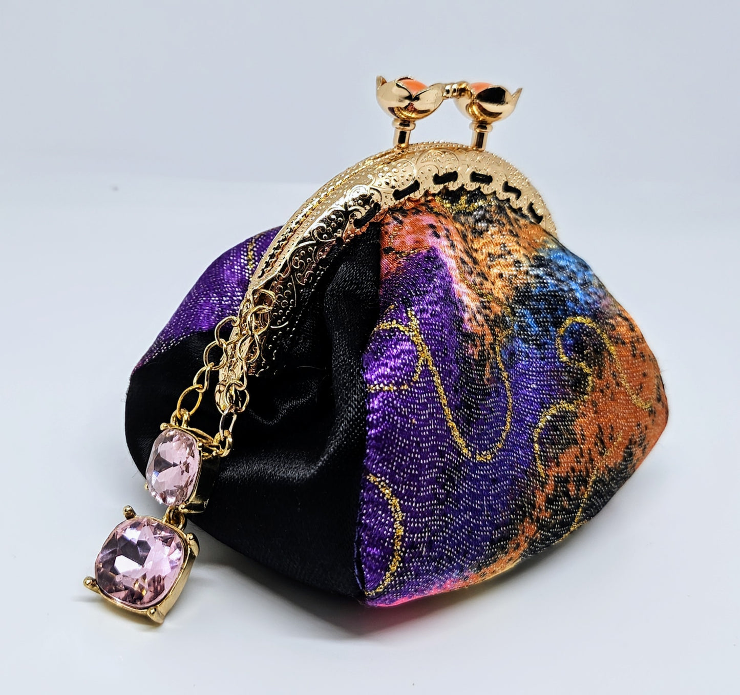 Side view of Metallic rainbow splash print kiss clasp coin purse with pink jewel charm