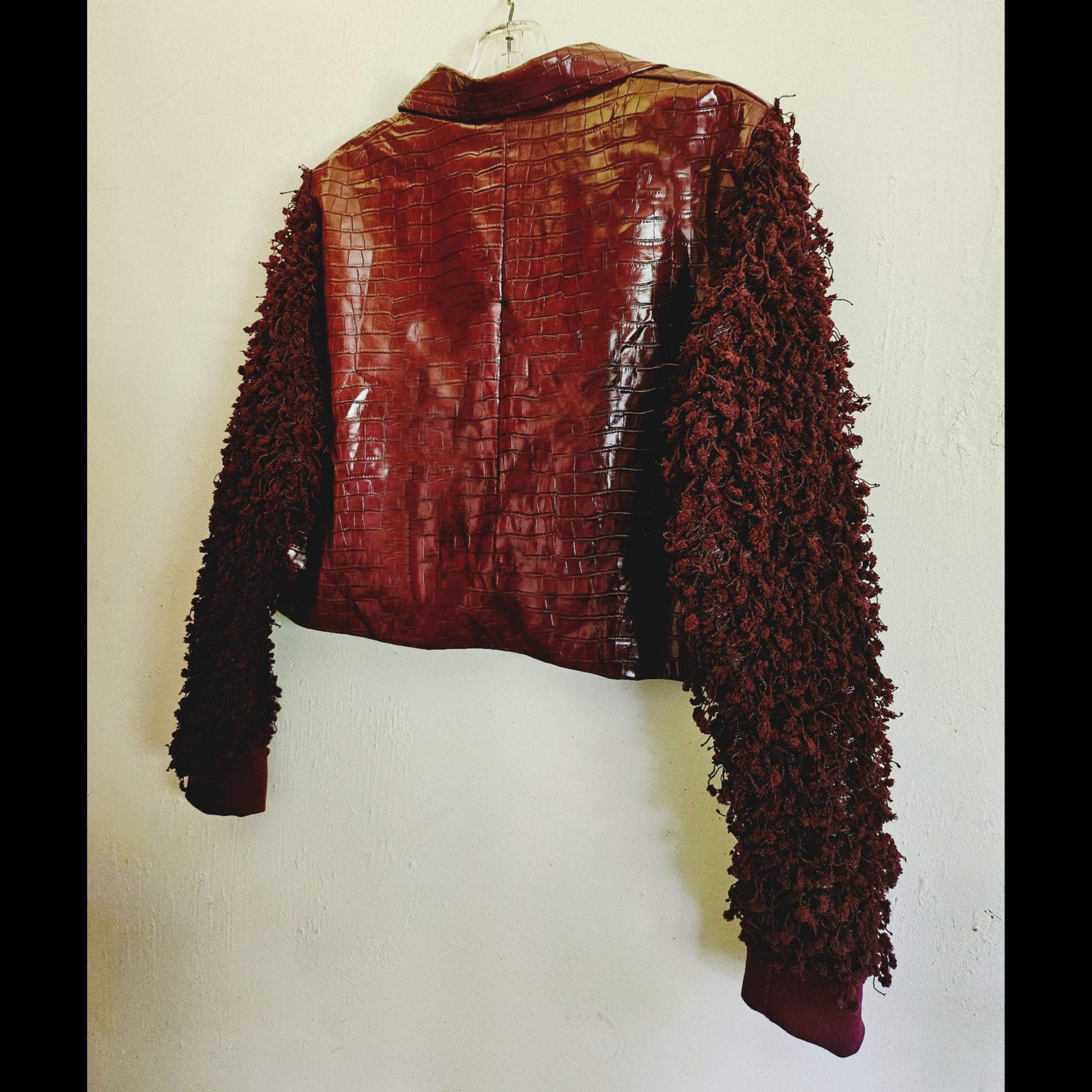 Side back view of burgundy croc embossed cropped jacket with fringe knit sleeves