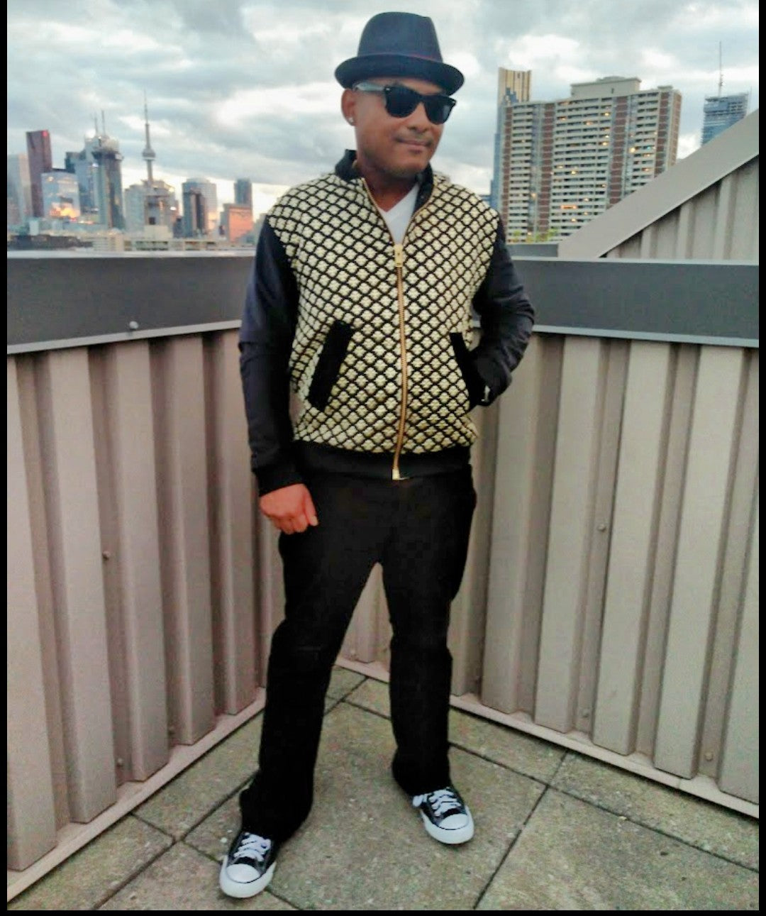 Male model wearing black and gold brocade bomber jacket in front of the Toronto skyline.