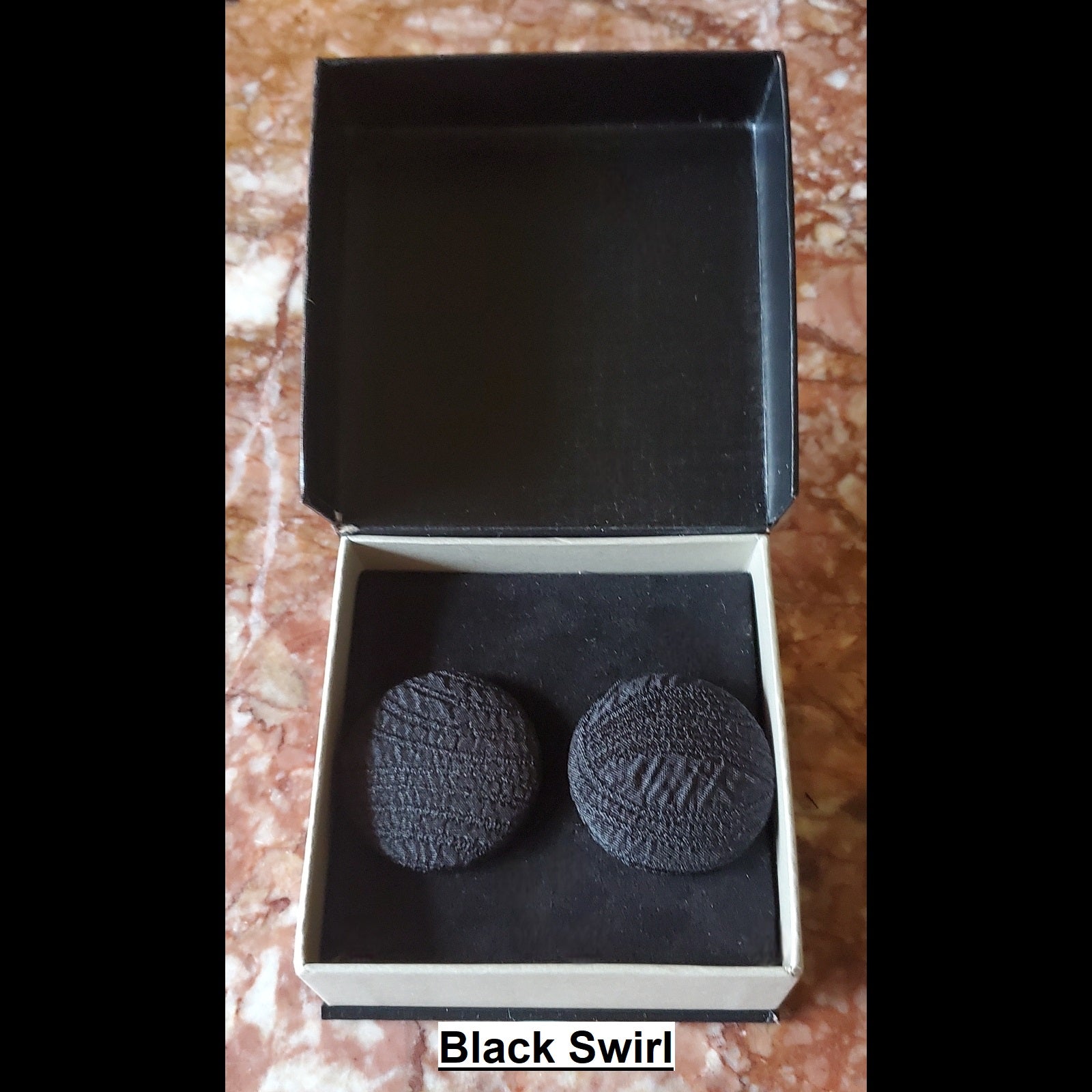 Textured black swirl embossed button earrings in jewelry box