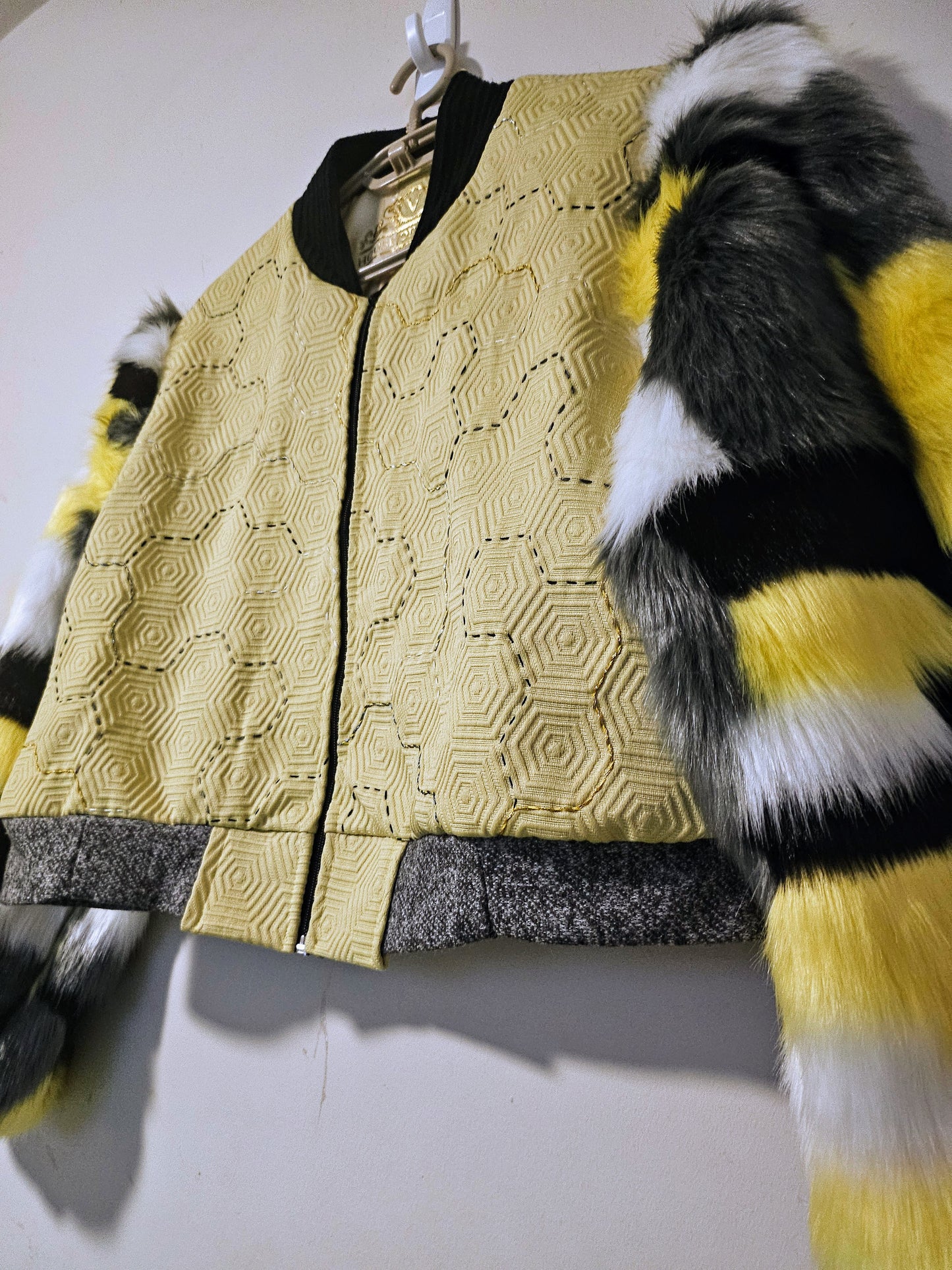Side view of Hand embroidered honeycomb print textured cropped bomber jacket with multi-coloured fur sleeves.