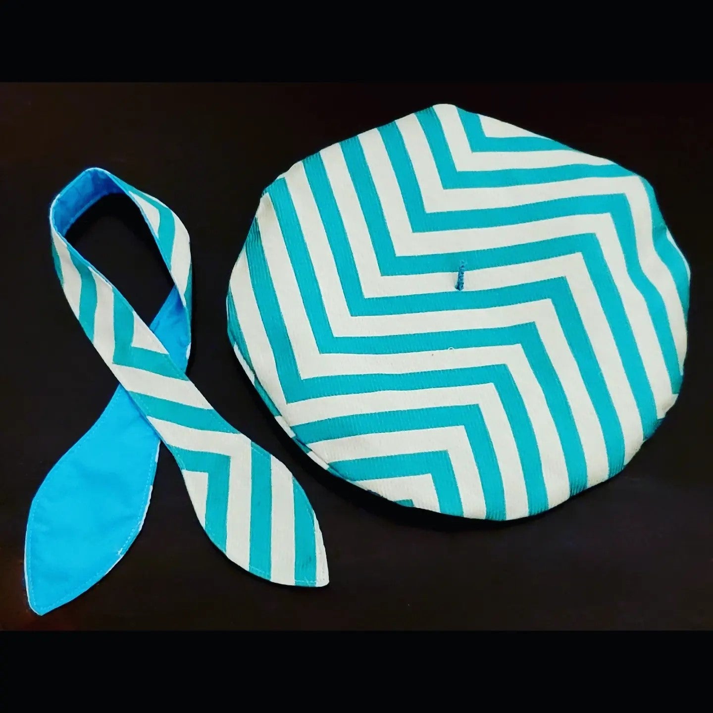 Turquoise and white chevron printed beret and matching scarf on brown background