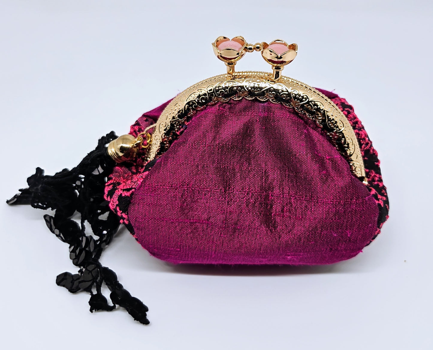 Front view of Magenta and black splash print kiss clasp coin purse with ornate lace tassel