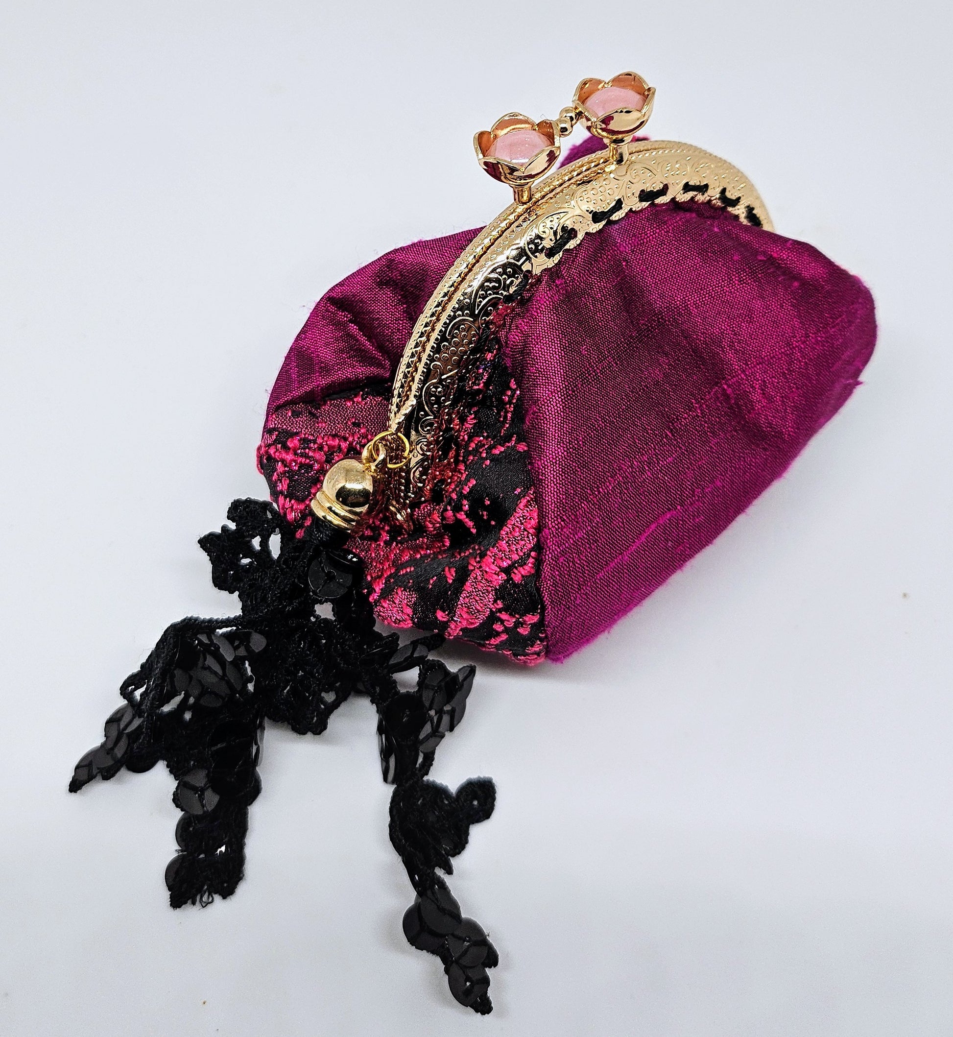 Side view of Magenta and black splash print kiss clasp coin purse with ornate lace tassel
