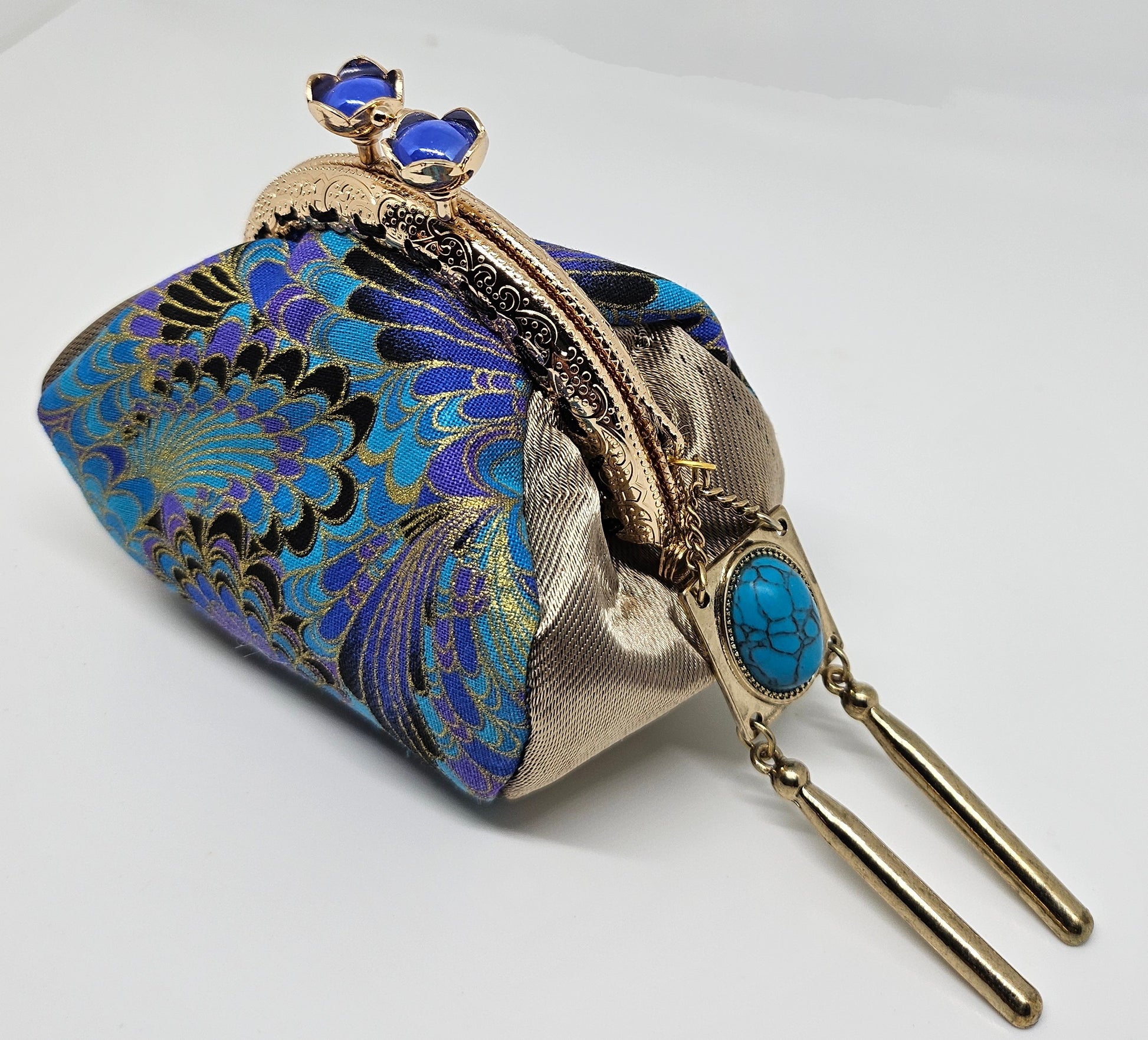 Side view of Peacock print kiss clasp coin purse with ornated jeweled tassel.