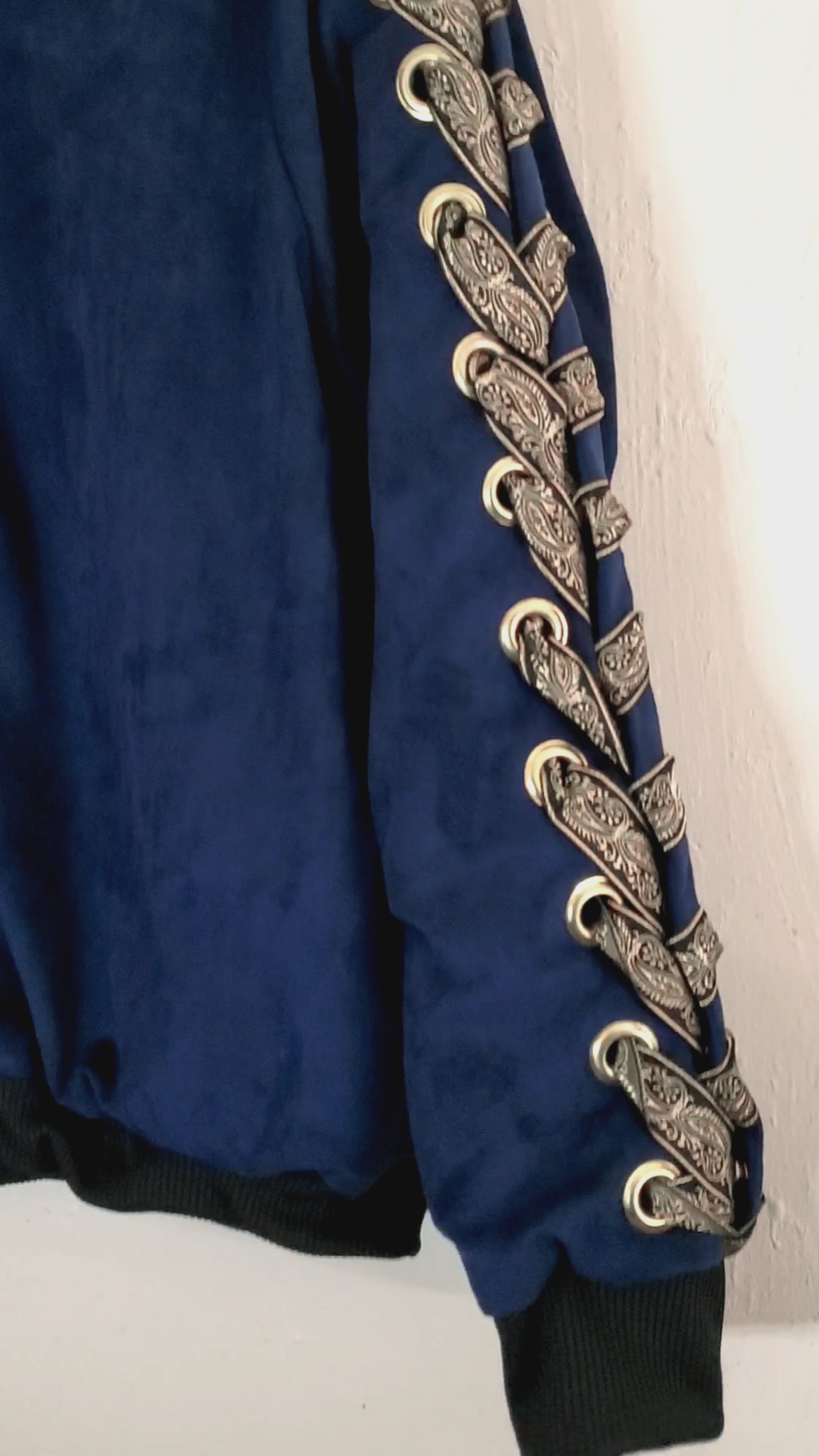 video of navy blue bomber jacket with gold lacing and eyelet front