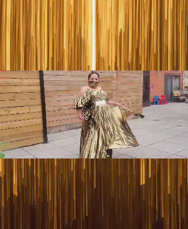 Video of model in a gold pleated dress and dancing.