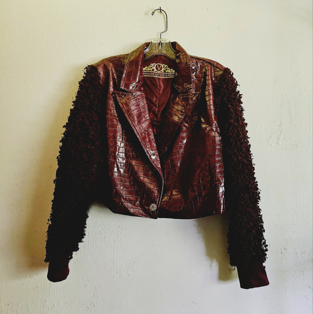Front view of burgundy croc embossed cropped jacket with fringe knit sleeves