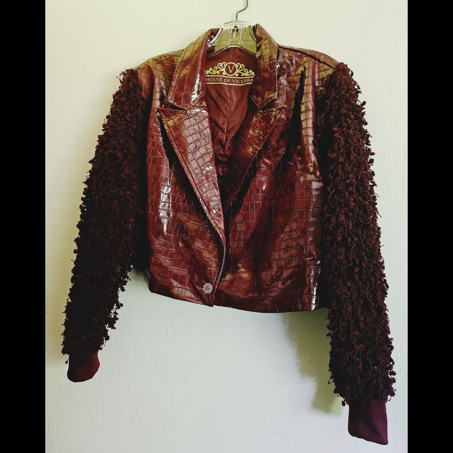 Side front view of burgundy croc embossed cropped jacket with fringe knit sleeves