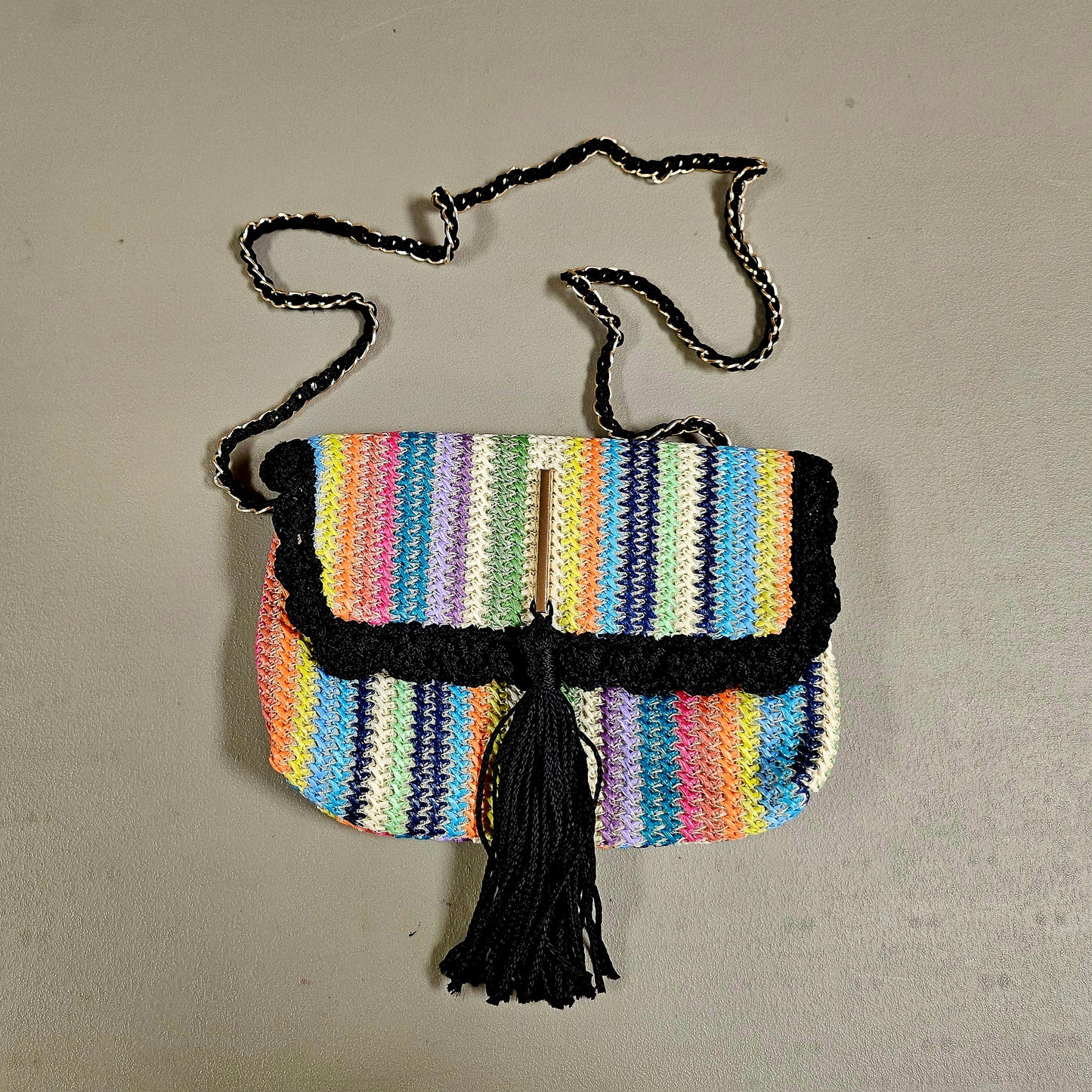 Top view of Rainbow striped crossbody with decorative tassel on surface