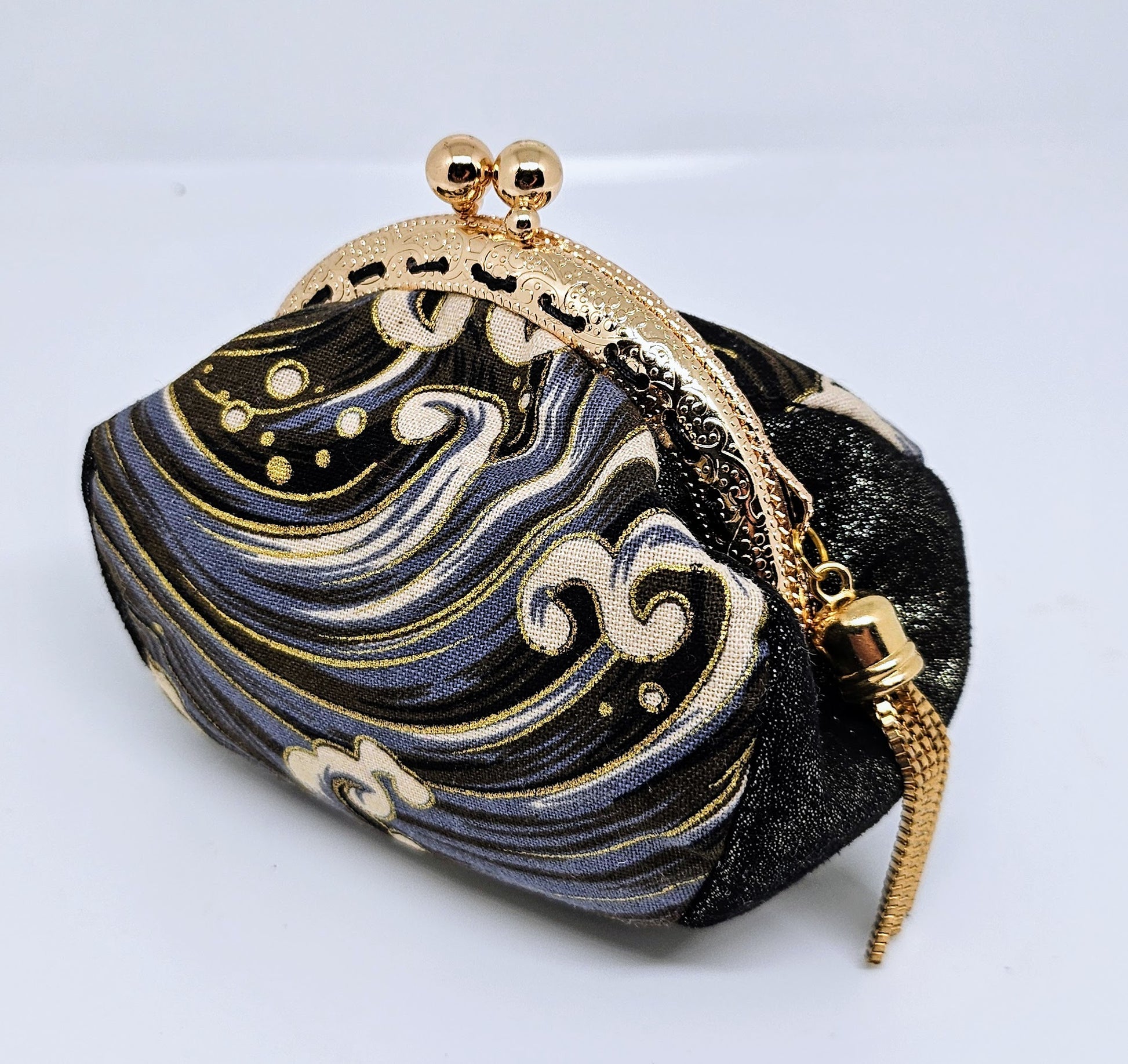 Side view of  Wave print kiss clasp coin purse with gold tassel