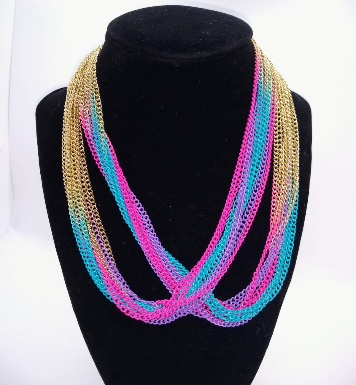 gold, purple, turquoise, and pink multi strand chain necklace on stand