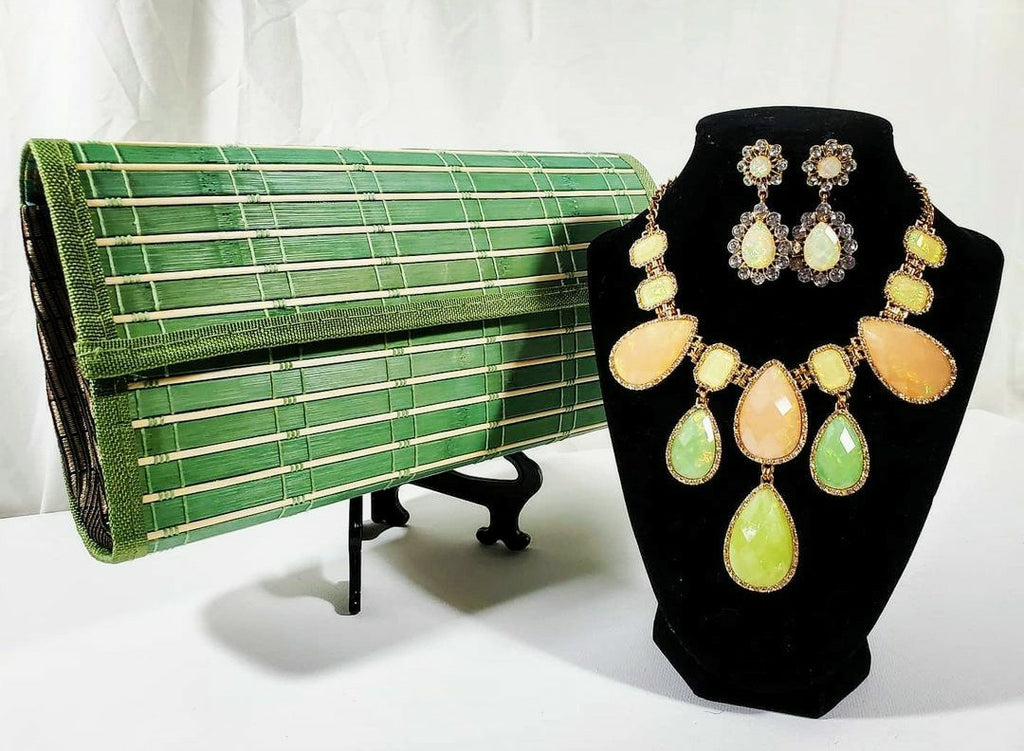 green wooden clutch beside citrus rhinestone chunky necklace and earring set on stand