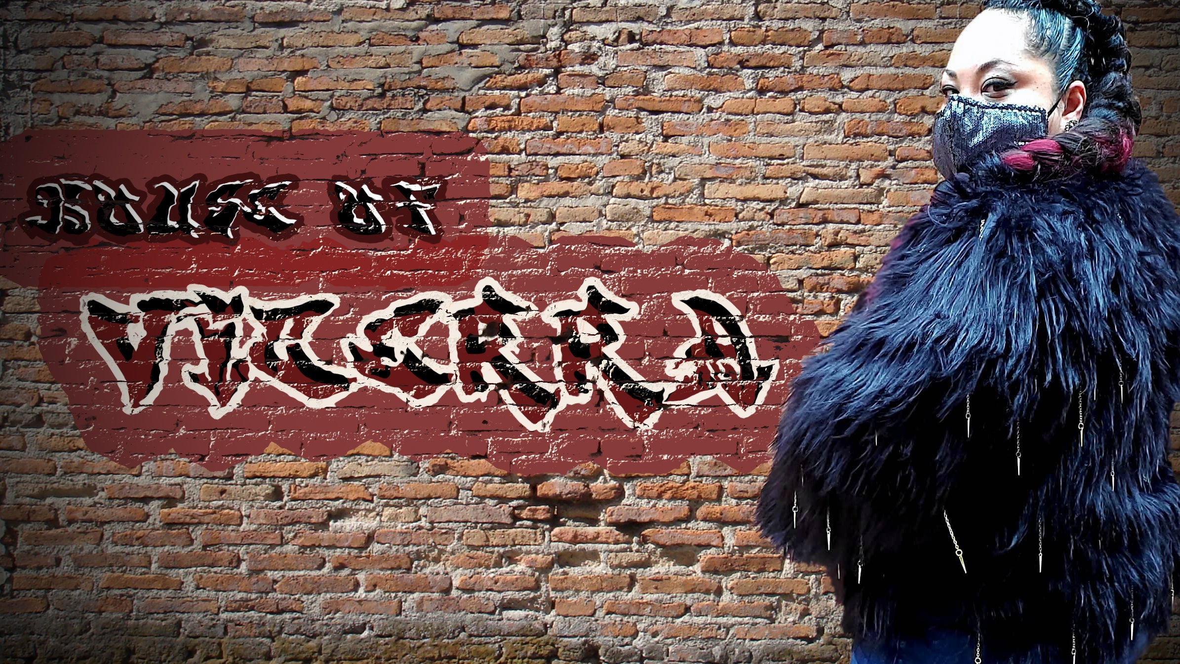 female model wearing black fur coat with chain tassels in front of a graffiti brick wall